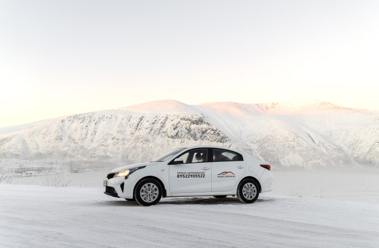 Белый Kia Rio с логотипом проката зимой в Кировске